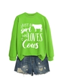 Detail of bright green sweatshirt featuring 'JUST A girl WHO LOVES Cows' print and denim shorts - Fluorescent Green (White Font)