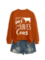 Flat lay of an orange sweatshirt with cow graphic and distressed denim shorts - Burnt Orange (White Font)