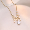 Elegante collana dorata con pendente in zircone a goccia su sfondo di seta champagne - Catena satellitare / Oro