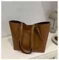 Detalle del bolso tote marrón caramelo mostrando la textura de cuero y logo en estante - Tostado