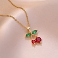 Elegante collana dorata con pendente a ciliegia in zircone rosso su sfondo di seta rosa - Collana a Ciliegia (X2664)