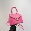 Pink tote bag with crocodile texture and golden clasp shown by a model - Pink