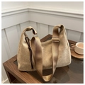 Detalle de bolso medialuna de ante beige con correa ancha ajustable de nailon en mesa - Caqui