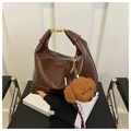 Detail der dunkelbraunen Lederhandtasche mit Goldverschluss und Plüschtier-Anhänger - Mit Anhänger / Braun