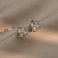 Elegante silberne Vierblatt-Blumen-Zirkon-Ohrstecker auf luxuriösem Seidenhintergrund - Rotierende Ohrringe / Silber