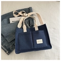 Navy canvas tote bag with front pockets and adjustable strap on white background - Blue