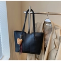 Detail of black tote bag with plush bear charm and woven tassel hanging on a rack - Black with Pendant