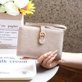 Primer plano de funda de pasaporte beige con hebilla de herradura dorada y correa - Albaricoque Beige