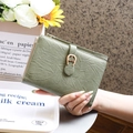 Close-up of avocado green leather wallet with textured finish and horseshoe metal buckle - Green