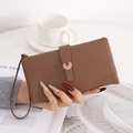 Detail einer braunen Clutch mit Litschi-Narbung, Hufeisenschnalle und Handgelenkschlaufe - Braun