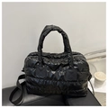 Close-up of shiny black quilted puffer bag texture with padded handles and strap - Black