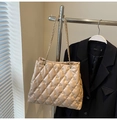 Detailansicht der aprikosenfarbenen Stepptasche mit goldener Kette am Kleiderbügel - Khaki