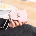 Detail der rosa PU-Leder-Geldbörse mit Herzschnalle und Handschlaufe, von Model gehalten - Rosa