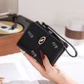 Close-up of black PU leather wallet with leaf embroidery and golden metal clasp details - Black