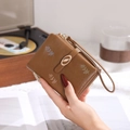 Detail of dark brown short wallet with floral embroidery and gold leaf clasp - Dark Coffee