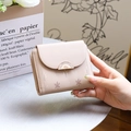 Détail du portefeuille rose à trois volets avec imprimé feuilles et boucle métallique - Abricot