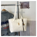 White quilted tote bag with golden lock and bell charm hanging on a metal rack - White