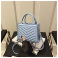 Detalle de mini bolso azul claro con acolchado en V y hebillas de metal dorado - Azul