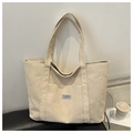 Detalle del bolso tote de pana en color crema que muestra la textura y la etiqueta - Caqui