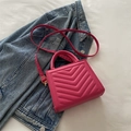 Magenta quilted crossbody handbag with gold hardware on blue denim background - Rose Pink