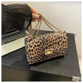 Detail view of the leopard print leather flap and golden metal clasp on a chain crossbody bag - Brown