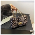 Detailed close-up of leopard print suede texture with premium gold metal lock and chain strap - Brown