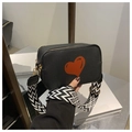 Detail of black pebbled leather crossbody bag featuring a red heart and geometric strap - Black