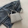 Silver quilted crossbody bag with V-shaped stitching and golden hardware on denim - Silver