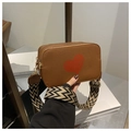 Detail of brown leather crossbody bag featuring red heart and geometric wide strap - Brown