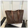 Detalle de un bolso tote grande de ante marrón con correas de cuero y remaches metálicos - café
