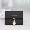 Short black bifold wallet for women featuring a gold leaf pendant and metal clasp - Black
