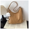 Detail of tan crescent shoulder bag with plush cloud charm on an open book background - Khaki with Pendant