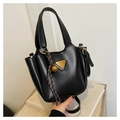Detail of black trapezoid bucket bag with gold triangle logo and bell charm accessory - Black