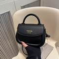 Classic black PU leather saddle bag with gold lettering and top handle shown in hand - Black