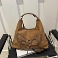 Brown suede tote bag with leather butterfly patch and cross lace detailing on a chair - Brown