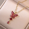 Dettaglio di una collana a farfalla dorata con zirconi rosso rubino in una scatola beige - Zirconia Rossa (X0246)