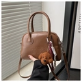 Detalle de bolso Boston marrón con logo grabado, colgante de osito y borlas tejidas - Marrón con colgante