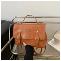 Detail of vintage brown leather backpack featuring embossed text and magnetic strap buckle - Brown