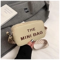 Close-up of beige lychee leather mini bag featuring bold letters and wide woven strap - Khaki