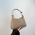 Warm beige shoulder bag with minimal gold bar and knotted handle shown in hand - Khaki