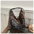 Detail of leopard print tote bag featuring a large black leather bow and cross-tie design - Brown