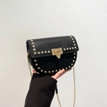 Black leather saddle bag with gold studs, chain strap, and metallic lock closure - Black