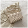 Detail of beige textured handbag showing V-shaped embossed leather on a blazer - Off White