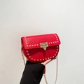 Red saddle bag with gold rivets and chain strap in a vibrant lychee grain finish - Red