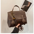 Detailed view of retro brown tote bag with metal buckles and artistic embossed text - With Charm / Brown