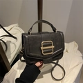 Dettaglio della trama in pelle nera vintage con fibbia dorata su una borsa a tracolla - Nero
