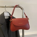 Detalle de bolso rojo oscuro con solapa, correa con nudo y logotipo dorado impreso - Rojo
