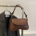 Detail of brown PU leather flap bag with gold FASHION & BAGS logo and sleek curved base - Coffee