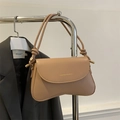 Detalle de bolso bandolera beige minimalista con base curva y correa de cuerda anudada - Caqui