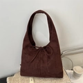 Bolso tote vintage de ante café oscuro con lazo decorativo sobre fondo de punto suave - Marrón